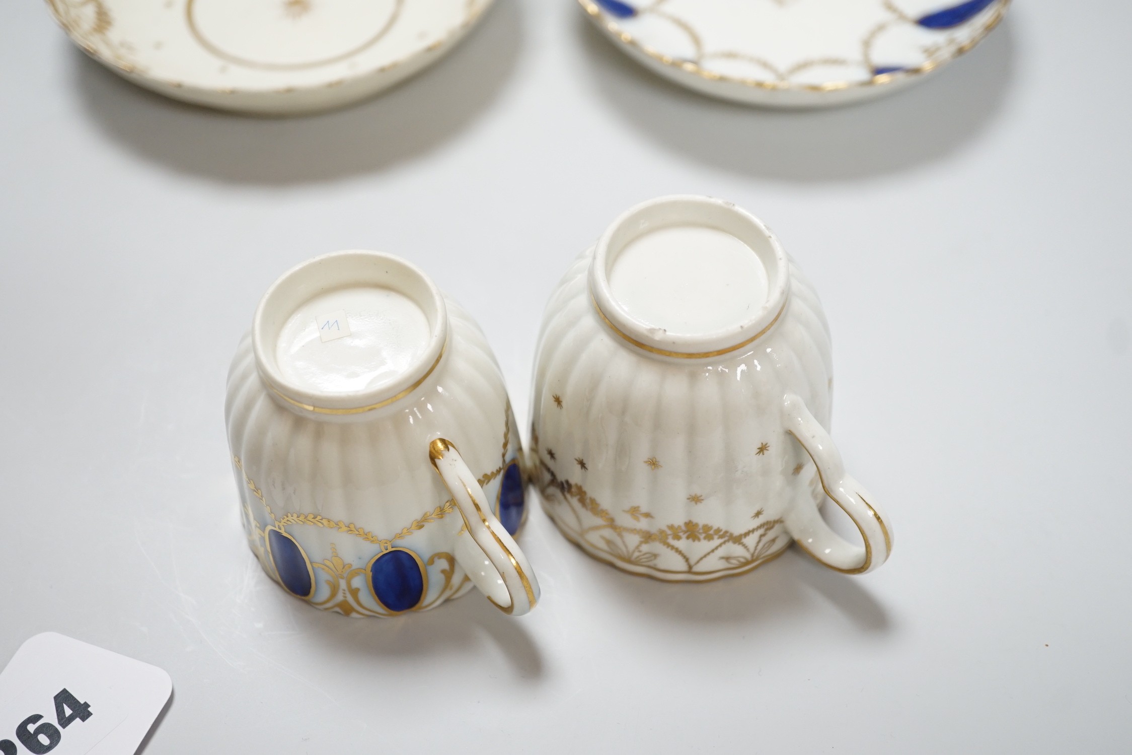 An 18th century Caughley coffee cup and saucer with blue pendants from gilt leafy swags and an 18th century Caughley coffee cup and saucer with an elaborately gilded border, both probably decorated at Chamberlains premis